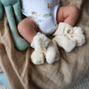 Soft cream organic cotton knit baby booties designed to keep newborn feet warm and comfortable, featuring a timeless neutral colour perfect for everyday wear or gifting.
