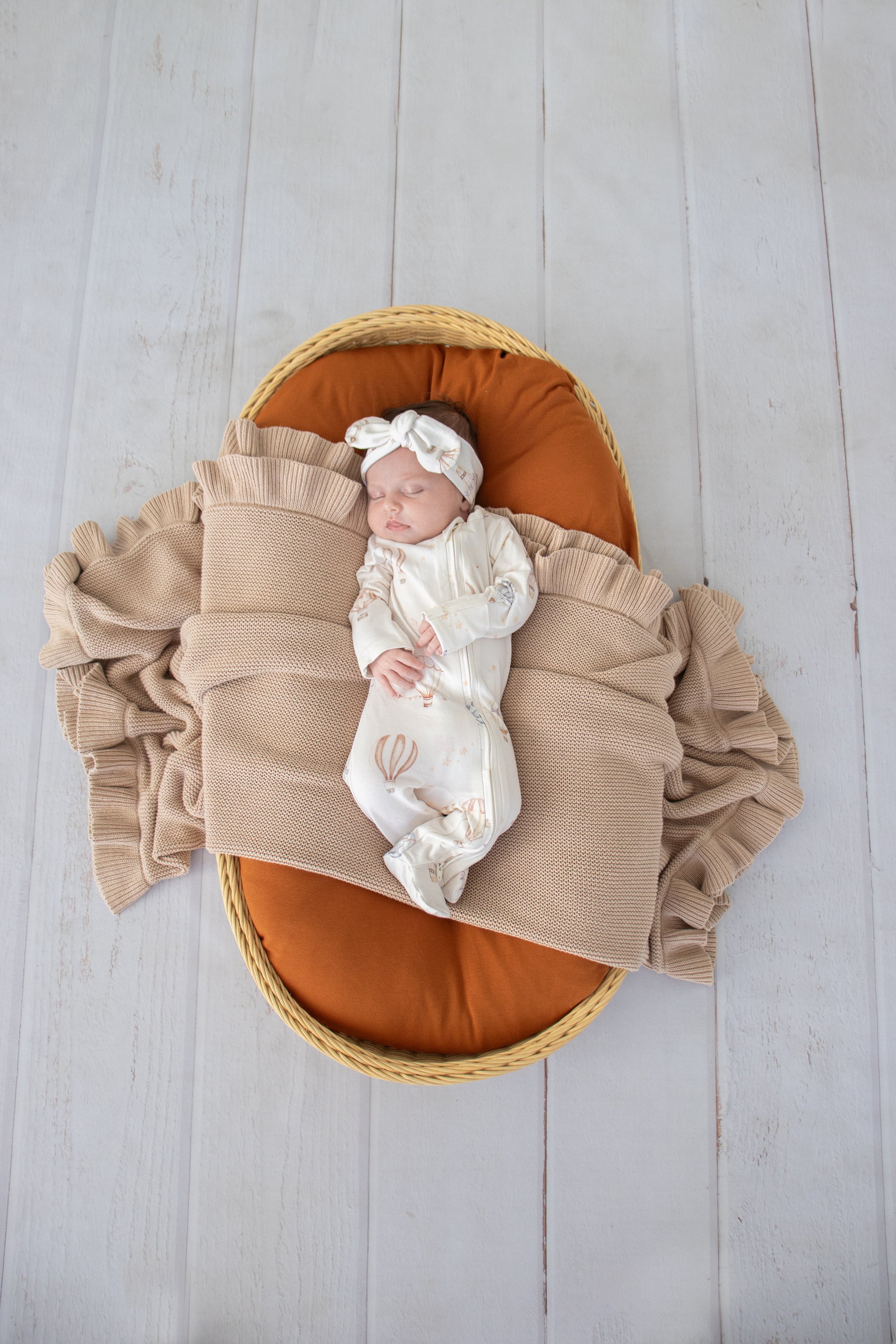 Baby wearing the Up & Away organic cotton zip footie with a hot air balloon print, featuring a two-way zip and enclosed feet for soft, comfortable day and night wear.