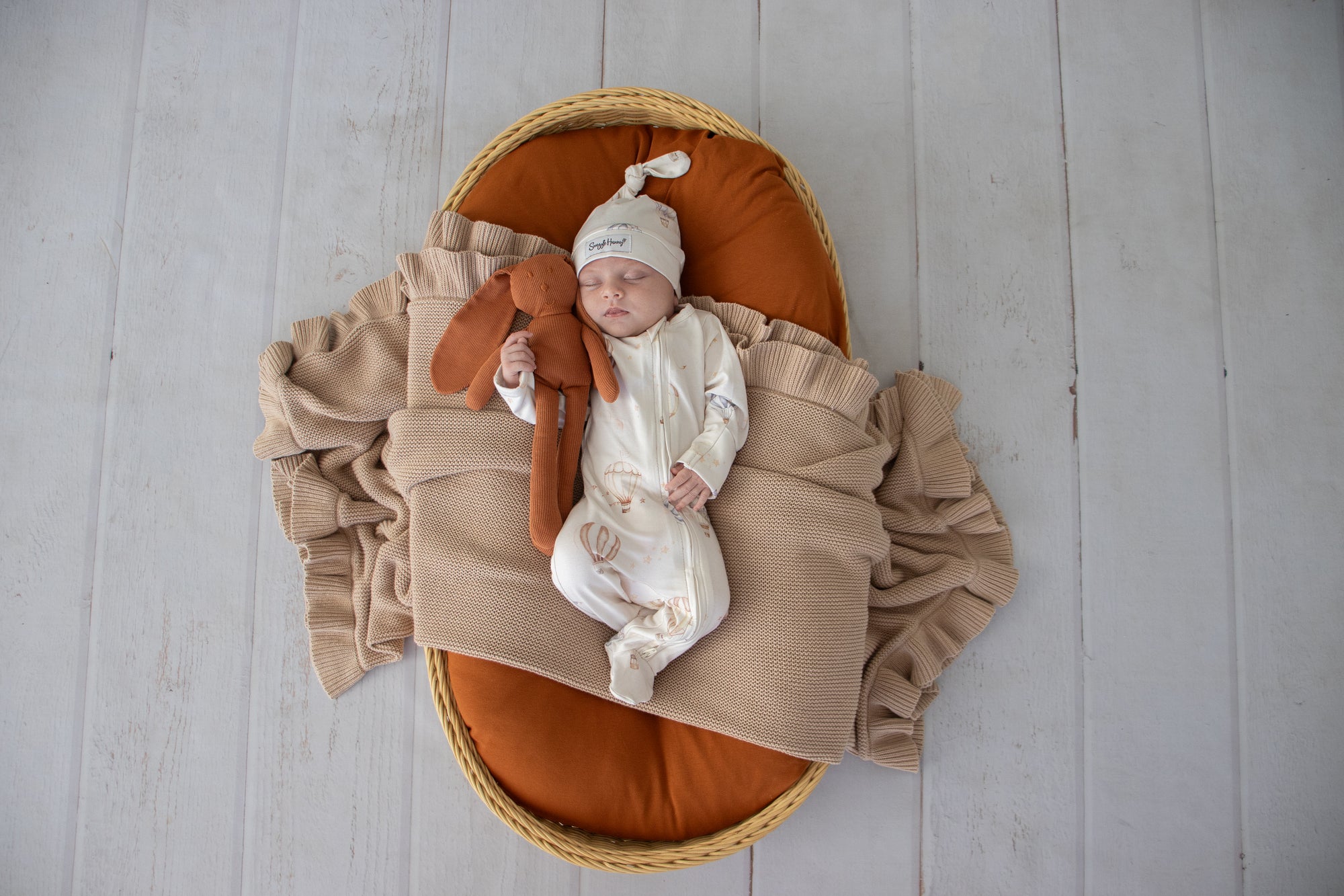 Baby wearing the Up & Away organic cotton zip footie with a hot air balloon print, featuring a two-way zip and enclosed feet for soft, comfortable day and night wear.
