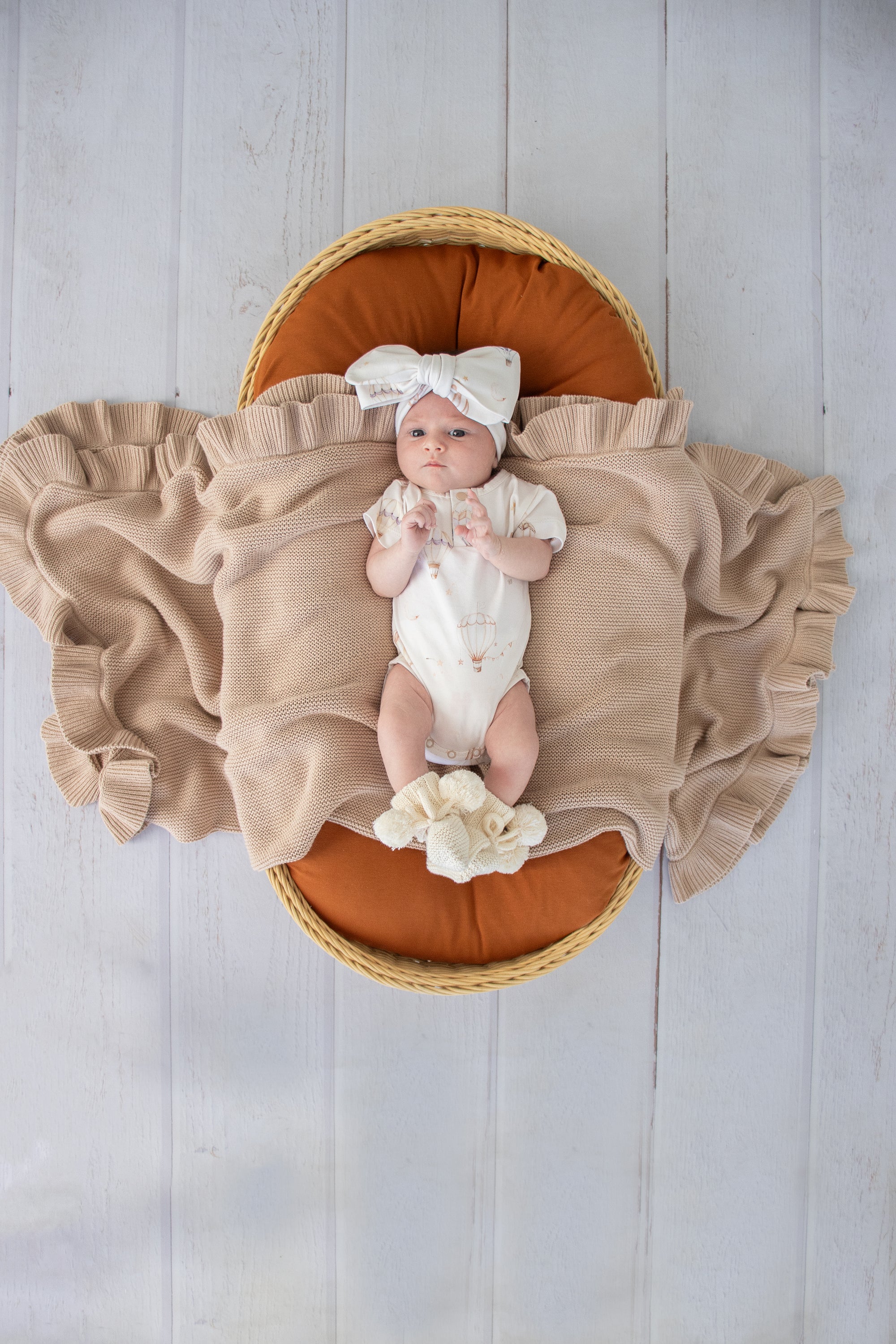 Soft cream organic cotton knit baby booties designed to keep newborn feet warm and comfortable, featuring a timeless neutral colour perfect for everyday wear or gifting.