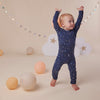 Baby wearing the Starry Night organic cotton convertible romper with fold-over feet and mittens, featuring a soft star print for comfortable day and night wear.
