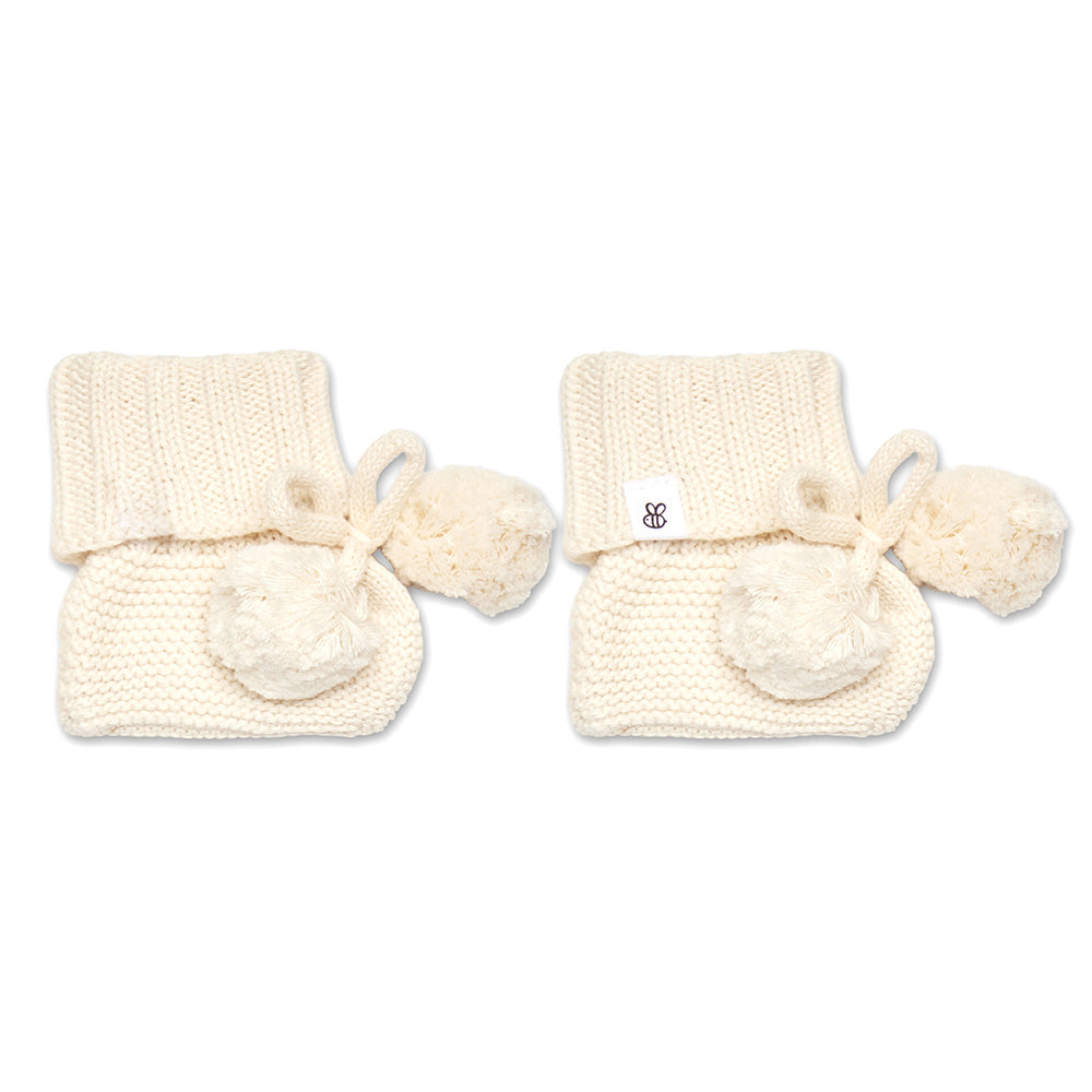 Soft cream organic cotton knit baby booties designed to keep newborn feet warm and comfortable, featuring a timeless neutral colour perfect for everyday wear or gifting.