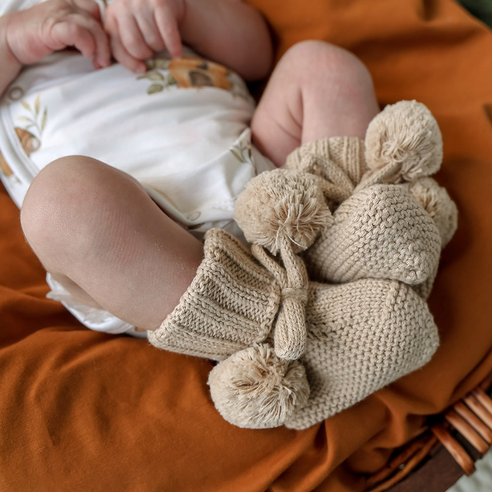 Soft hazelnut organic cotton knit baby booties designed to keep newborn feet warm and comfortable, featuring a timeless neutral colour for everyday wear or gifting.