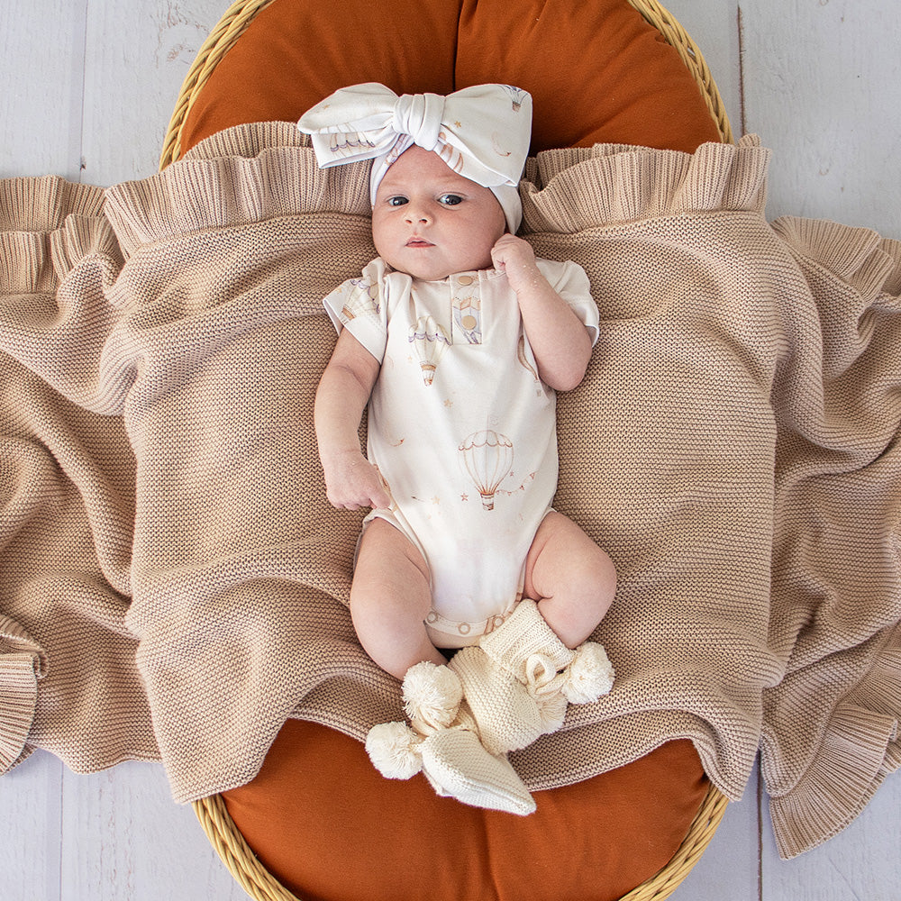 Soft cream organic cotton knit baby booties designed to keep newborn feet warm and comfortable, featuring a timeless neutral colour perfect for everyday wear or gifting.