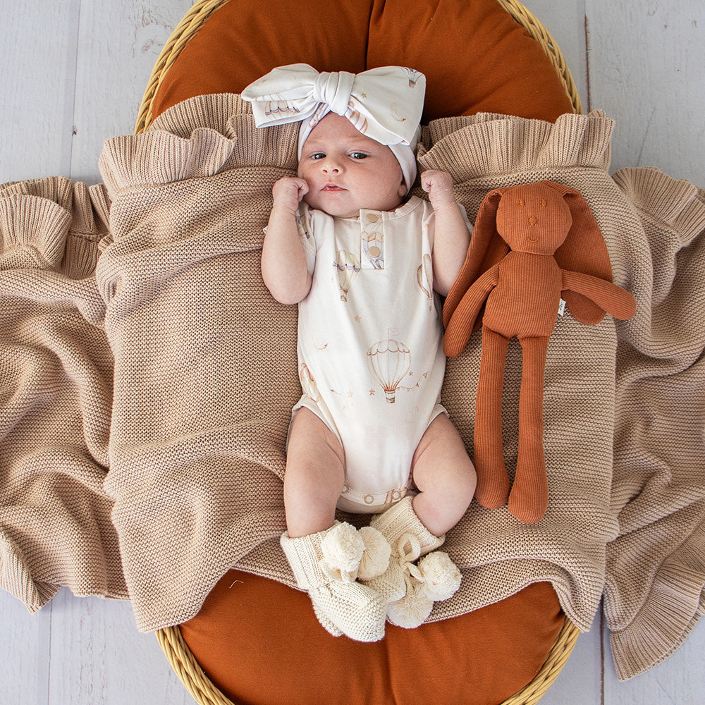 Soft cream organic cotton knit baby booties designed to keep newborn feet warm and comfortable, featuring a timeless neutral colour perfect for everyday wear or gifting.
