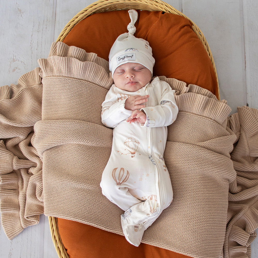 Baby wearing the Up & Away organic cotton zip footie with a hot air balloon print, featuring a two-way zip and enclosed feet for soft, comfortable day and night wear.